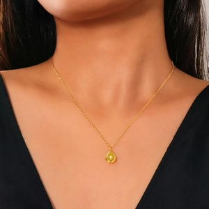 Detail of a vintage gold drop pendant necklace with a starburst gem on a model's neck