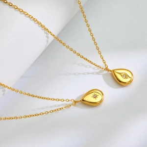 Detail showing two gold teardrop necklaces with engraved star and centered crystals