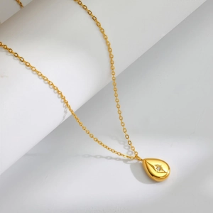 Vintage 18K gold plated teardrop pendant necklace with starburst design on a white pedestal