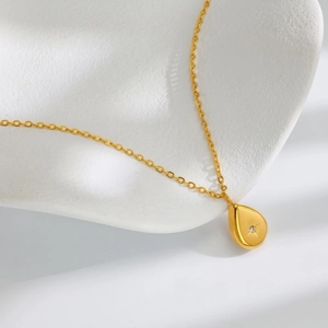 Vintage gold-plated teardrop starburst necklace with centered gemstone on white display