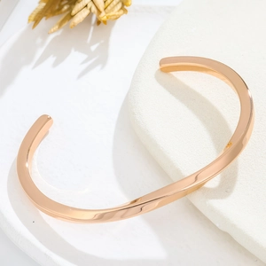 Gros plan détaillé d'un bracelet jonc spirale en or rose sur un socle en pierre