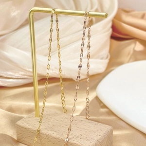 Minimalist titanium steel anklet in gold and rose gold on a luxury display stand