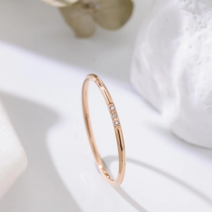 Three-diamond minimalist 18k rose gold titanium steel ring for women shown on white stone