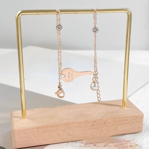 Detalle del colgante de llave en oro rosa con números romanos y perla en soporte