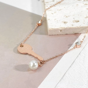 Pulsera de oro rosa con colgante de llave, perla y detalles de circonita brillante