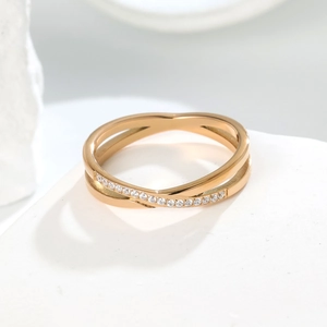 Macro view of rose gold criss-cross ring with micro-pave crystals on stone background