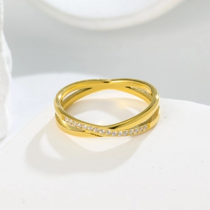 Macro detail of gold-plated criss-cross ring featuring micro-pave cubic zirconia inlay