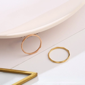 Anillos de onda minimalistas de 1mm en oro y oro rosa sobre elegantes soportes blancos
