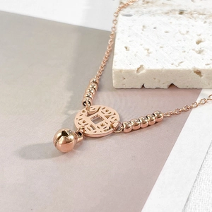 Nahaufnahme der roségoldenen Fußkette mit antikem Münzanhänger und einer kleinen Glocke