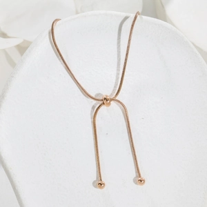 Detailed view of adjustable rose gold snake chain bracelet with slider bead and polished finish