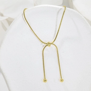 Close-up of golden adjustable snake chain with slider clasp and polished beads