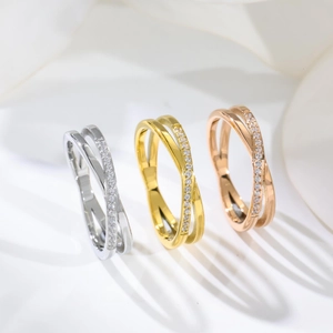 Three elegant crossover rings in gold, silver, and rose gold with pavé diamonds