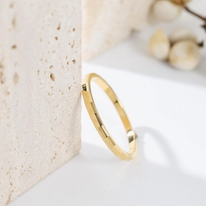 Macro shot of geometric faceted gold titanium ring on textured stone with dry flowers