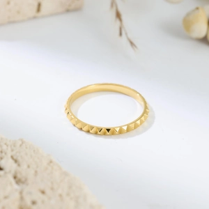 Detail view of 18K gold plated titanium ring featuring pyramid stud texture on white background