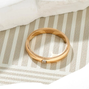 Macro shot of minimalist gold titanium ring featuring a single sparkling center crystal