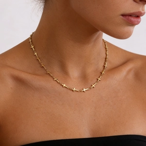 Close-up of a gold cross chain necklace on a model showing the dainty choker length