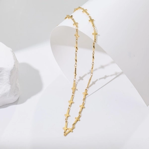 Close-up of polished gold cross link necklace draped on minimalist white stone display