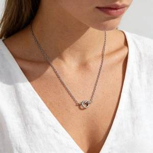 Détail d'un collier avec pendentif nœud en argent minimaliste porté avec lumière douce
