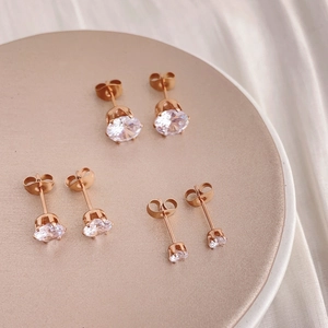 Set of three rose gold cubic zirconia stud earrings in varied sizes on a metal display tray