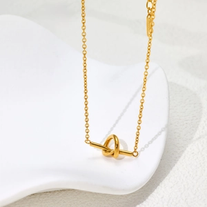 Détail du collier noeud en or 18 carats sur plateau blanc avec ombres élégantes