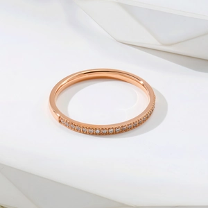 Bague minimaliste en acier titane or rose avec serti demi-cercle de zircons sur fond blanc