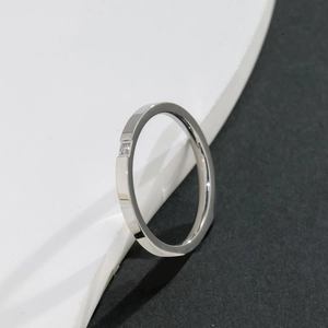 Macro shot of minimalist silver titanium ring with embedded square zircon on textured surface