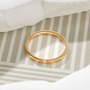 Close-up of minimalist thin gold titanium ring featuring a single sparkling diamond stone