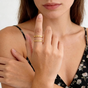 Detalle de anillos apilables de acero de titanio dorado con grabados de estrellas y geométricos