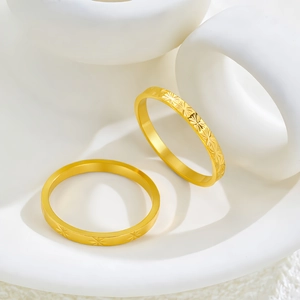Detalle macro de anillos apilables de titanio chapados en oro con grabados de rayos de sol