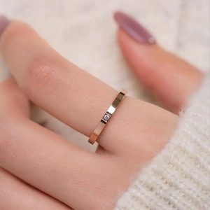 Minimalist rose gold titanium steel ring with a single square zircon on model's finger