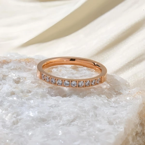 Détail macro d'une bague en titane or rose sertie de zircons sur pierre blanche