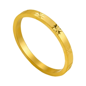 Detalle macro de anillo de titanio dorado con grabados de estrellas y bordes planos pulidos