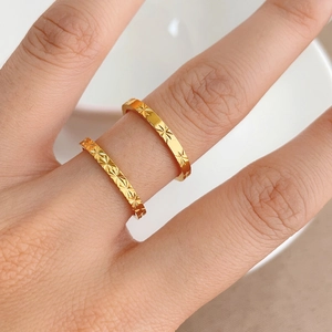 Detalle de dos anillos de acero de titanio dorado con textura de estrella en dedos
