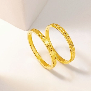 Detalle de dos anillos de acero de titanio dorado con grabados de estrellas en piedra
