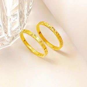 Detalle de dos anillos de acero de titanio dorado con grabados de flores de estrella