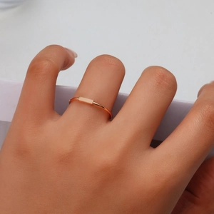 Vista macro de un anillo rectangular minimalista chapado en oro rosa de 18 quilates