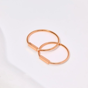 Vista macro de pendientes de aro en oro rosa con dijes rectangulares minimalistas