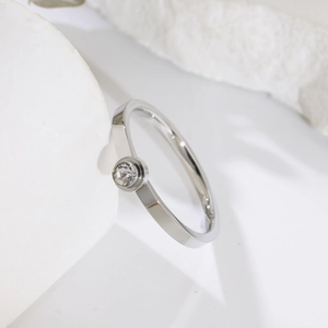 Dettaglio ravvicinato di un anello solitario in argento con zirconia su fondo in pietra