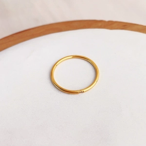 Minimalist gold band ring with tiny gemstone inlay on a clean white tray