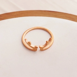 Dettaglio ravvicinato dell'anello a corna d'oro rosa su un elegante supporto in legno