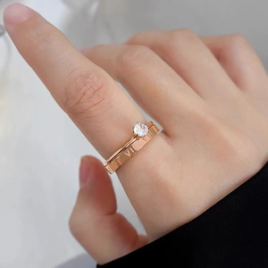 Detail of rose gold double-layered ring with zircon stone and Roman numeral engraving