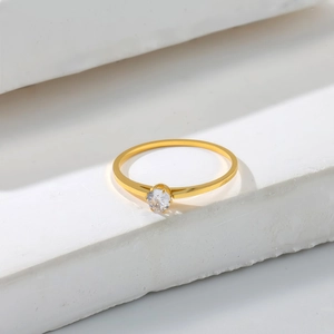 Macro view of minimalist gold four-prong ring with a round clear zircon stone