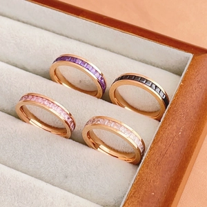 Detailed macro of rose gold eternity rings set with square-cut gems in four vibrant colors