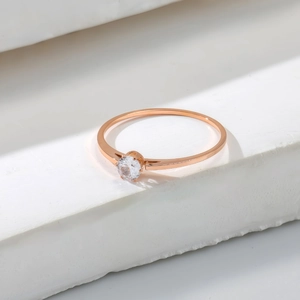 Elegant rose gold solitaire ring with round brilliant-cut stone on white stone pedestal