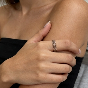 Detail of rose gold cutout ring with Greek fret design worn on the index finger