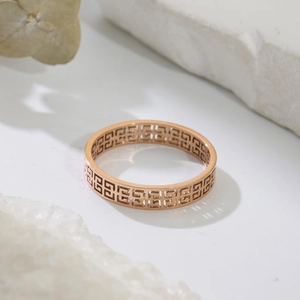 Close-up of rose gold stainless steel ring featuring hollow geometric Greek key patterns