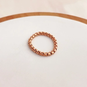 Detailansicht eines roségoldenen Kettengliedrings mit poliertem Finish auf Podest
