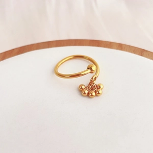 Close-up of gold open ring with hanging beads and smooth metallic reflective finish