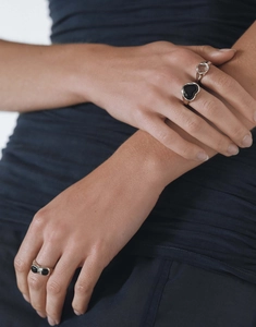 Détail d'une bague en cœur avec pierre noire et bijoux géométriques en argent
