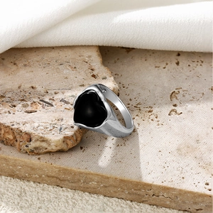 Détail d'une bague vintage argentée avec pierre en forme de cœur noir sur socle en pierre